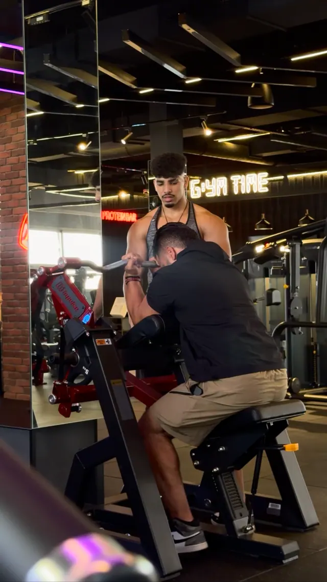 Un coach accompagne un adhérent sur une machine de musculation